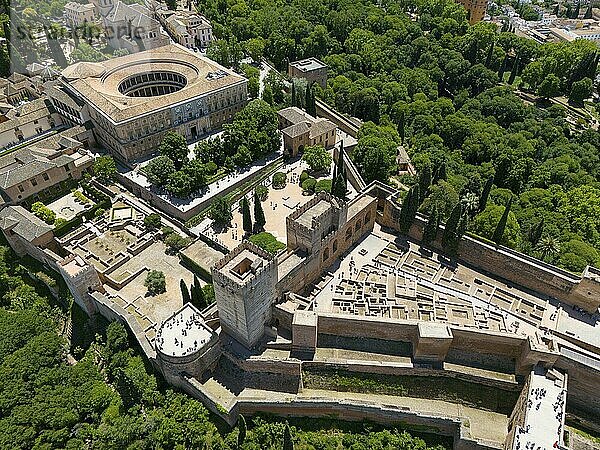 Luftaufnahme eines Schlosskomplexes mit umliegender Mauer  umgeben von grüner Vegetation und Stadtlandschaft  Luftaufnahme  Alhambra  Andalusien  Granada  Spanien  Europa