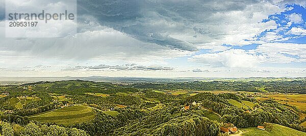 Luftbildpanorama von grünen Hügeln und Weinbergen mit Bergen im Hintergrund. Österreich Weinberge Landschaft. Leibnitz Gebiet in der Südsteiermark  Weinland. Toskana wie Ort und berühmter Touristenort