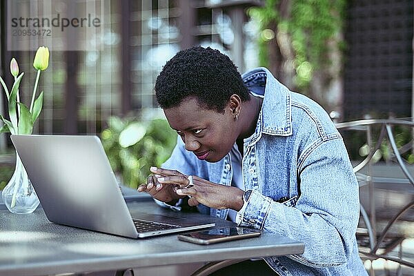 Person intently looks at his laptop screen while working outdoors  showing a modern remote workspace