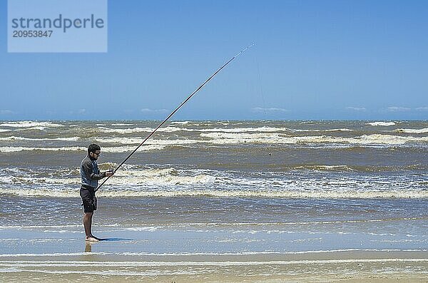 Junger Mann beim Angeln am Strand  Sportfischen