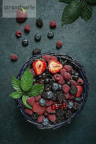 Mischung aus frischen Beeren  in einem Korb  auf einem grauen Holztisch  keine Personen  Ansicht von oben