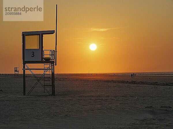 A rescue tower against the silhouette of a bright orange sunset on the beach  juist  east frisia  germany