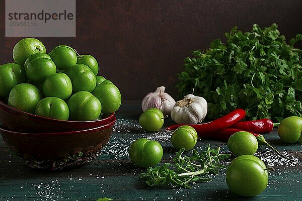 Tkemali  grüne Kirschpflaume  mit Zutaten für Sauce  Koriander  Minze  Paprika  Knoblauch  auf einem Holztisch  Nahaufnahme  rustikal  Lebensmittel Hintergrund  keine Menschen  selektiver Fokus