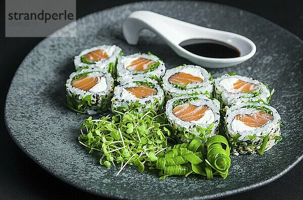 Perfektes Sushi  traditionelle japanische Küche. Köstliche Uramaki mit Shoyo Sauce auf dem dekorierten Teller  schwarzer Hintergrund