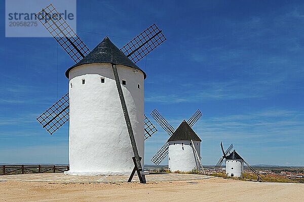 Drei weiße Windmühlen mit schwarzen Dächern in einer trockenen Landschaft mit klarem blauem Himmel  Alcazar de San Juan  Ciudad Real  Kastilien-La Mancha  Route des Don Quijote  Spanien  Europa