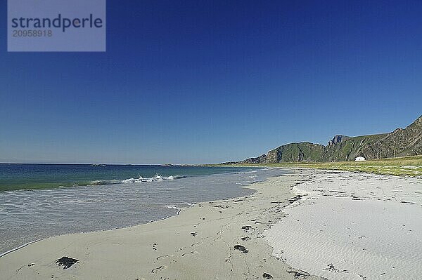 Schöner Strand mit klarem blauem Himmel  sanften Wellen und Bergen im Hintergrund  Bleik  Vesteralen  Langoya  Nordland  Norwegen  Europa