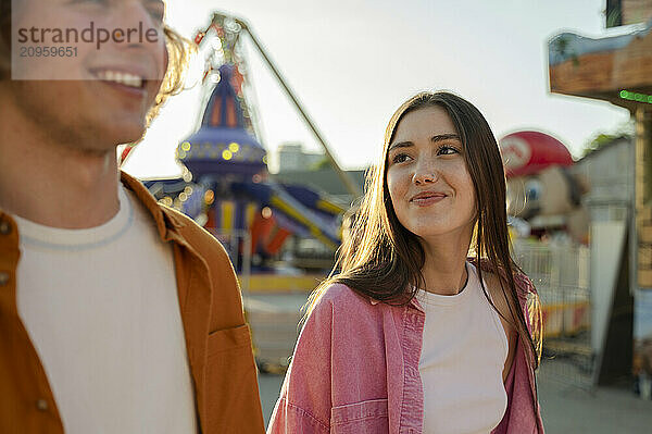 Happy girlfriend looking at boyfriend and walking in amusement park