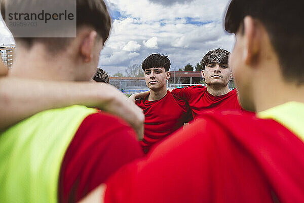 Teenager soccer players huddling under cloudy sky