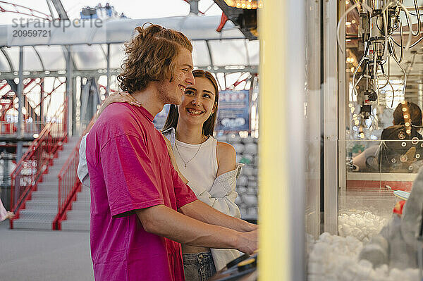 Happy couple having fun playing toy grabbing game at amusement park