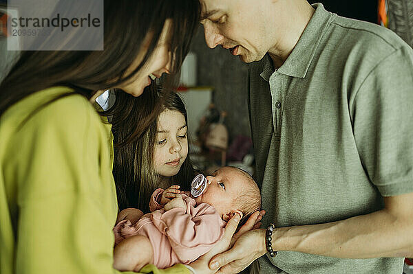 Family spending leisure time with newborn baby girl at home