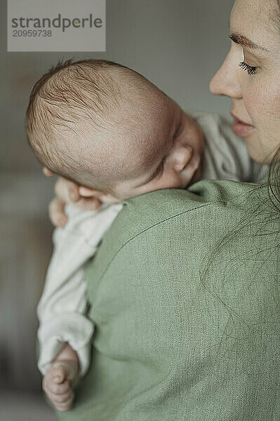 Baby boy sleeping on mothers shoulder at home