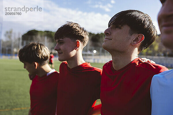 Smiling soccer players standing together under sky