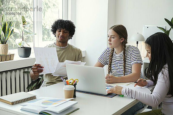 Curly hair man studying with friends at home