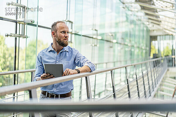 Experienced businessman using digital tablet standing in office building