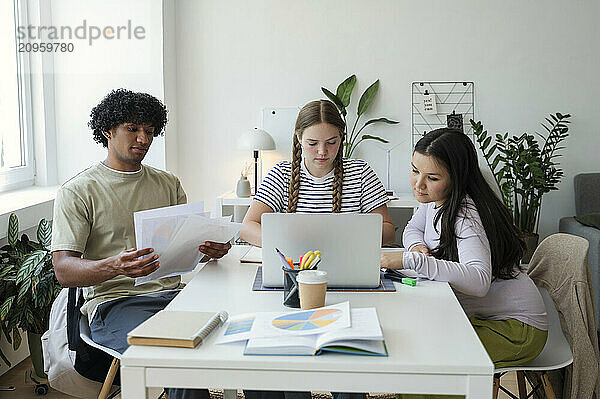 Focused multiracial friends studying at home