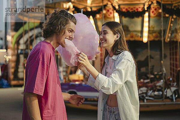 Couple eating cotton candy at amusement park