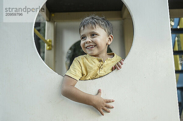 Smiling boy looking through circle of playing equipment at playground