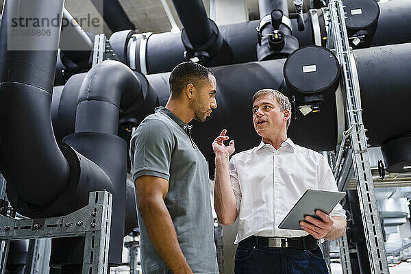 Employee and businessman with digital tablet talking in factory