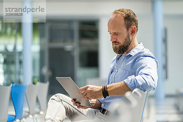 Businessman sitting in company auditory using digital tablet