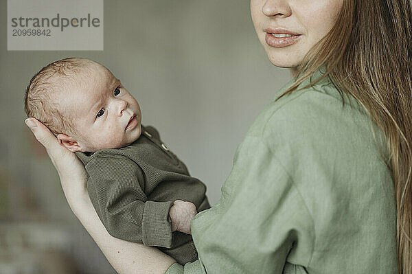 Mother carrying newborn baby at home