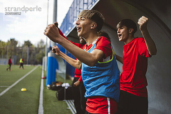 Cheerful soccer players celebrating victory on field