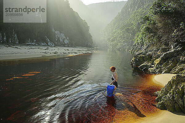 Woman in swimsuit crossing Lottering River at Otter Trail in Tsitsikamma Section  Garden Route National Park  Eastern Cape  South Africa