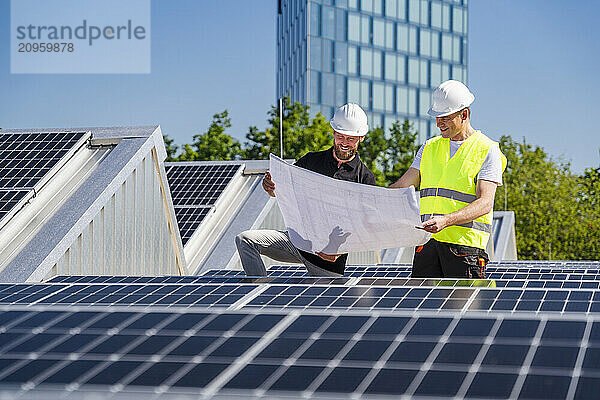 Two technicians strategizing on the rooftop of a corporate building adorned with solar panels