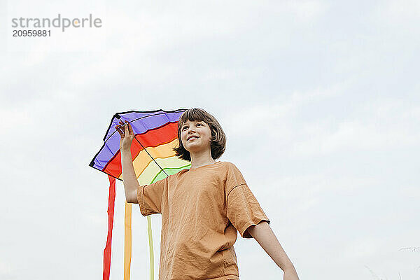 Girl holding kite under white sky