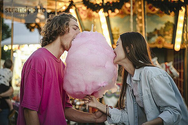 Happy couple eating cotton candy at amusement park