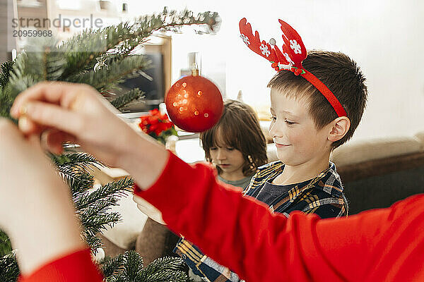 Children decorating Christmas tree at home