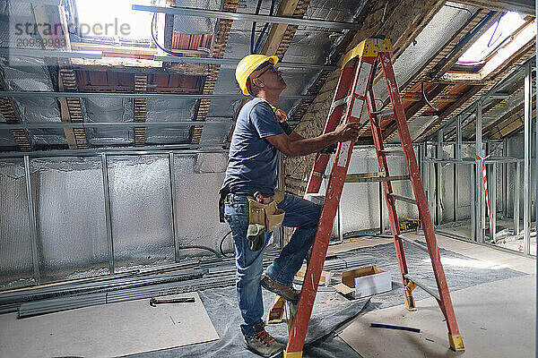 Construction worker climbing on ladder at site