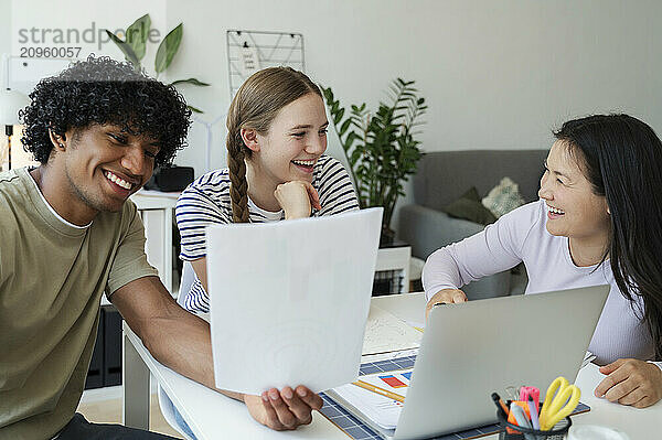 Happy multiracial friends doing group study at home