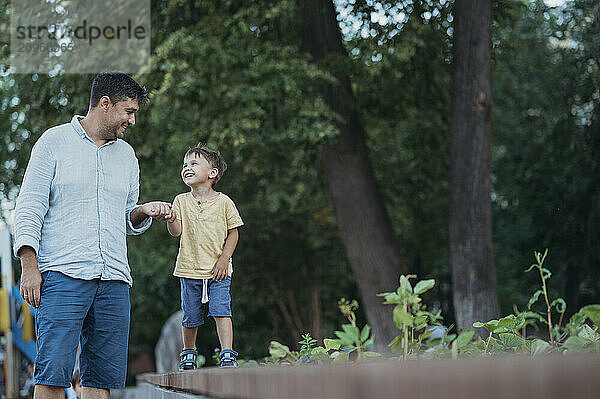 Father and son holding hands walking in garden