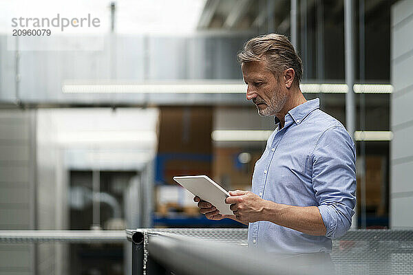 Senior businessman using tablet PC at factory