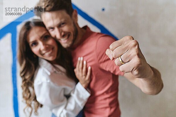 Happy woman with man punching in front of wall at site