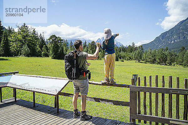 Girl with father pointing at mountain in sunny day