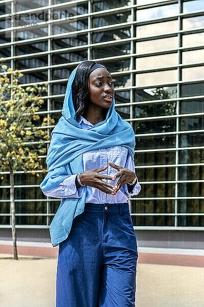 Businesswoman in hijab standing and gesturing near office