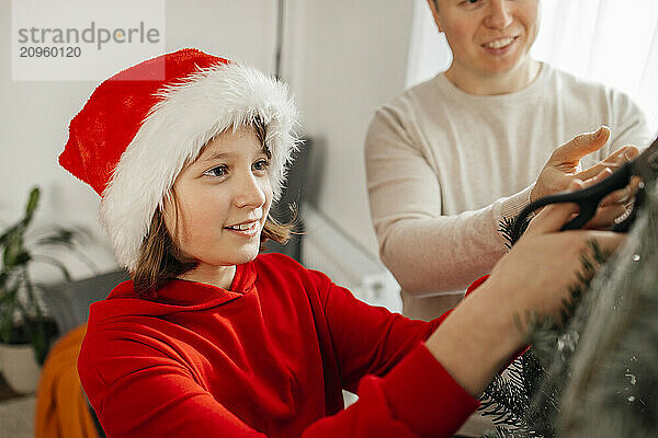 Girl cutting net of Christmas tree at home