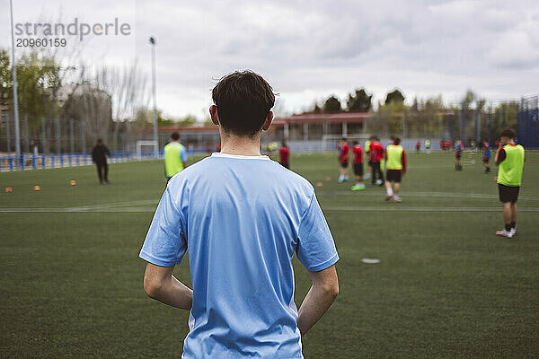 Soccer team having match on field under cloudy sky