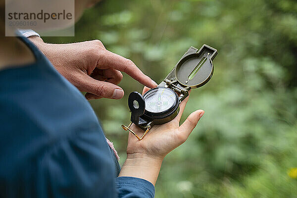 Girl with mother hiking and using compass in forest