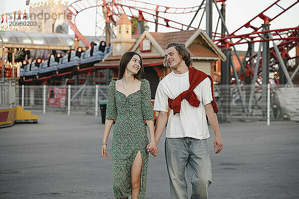 Romantic couple holding hands and walking in amusement park