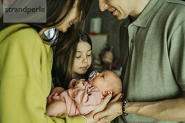 Family spending leisure time with newborn girl at home