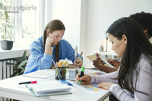 Focused woman doing homework with friends at home