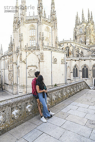 Man leaning on railing with girlfriend in front of Burgos Cathedral