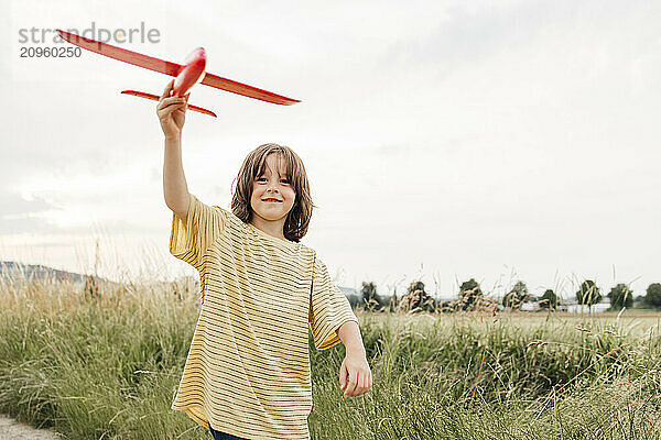 Boy holding red airplane toy on field