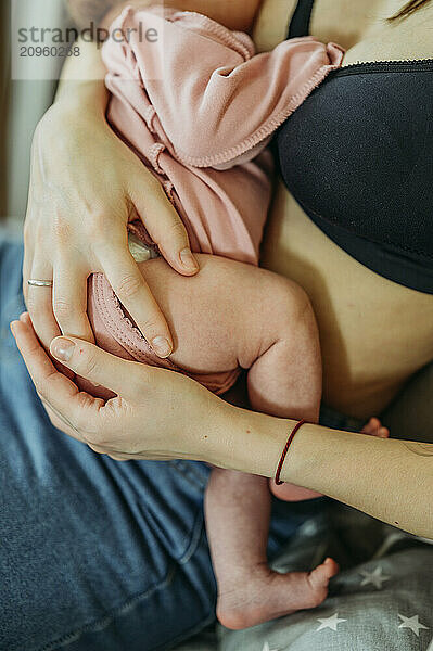 Mother breastfeeding newborn baby girl at home