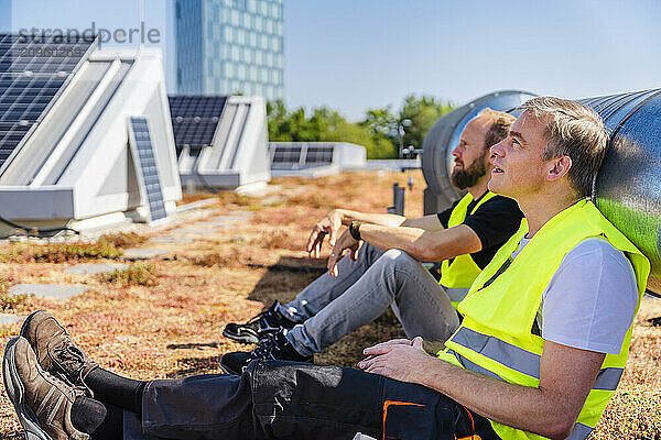 Two solar panel technicians taking a well-deserved break on the rooftop of a company building