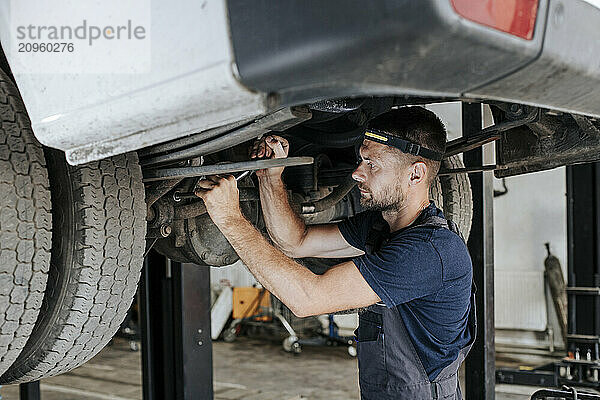 Technician busy repairing vehicle in garage.