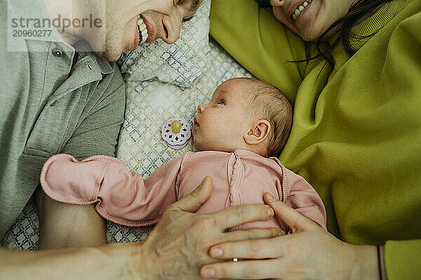 Parents lying on bed with newborn baby