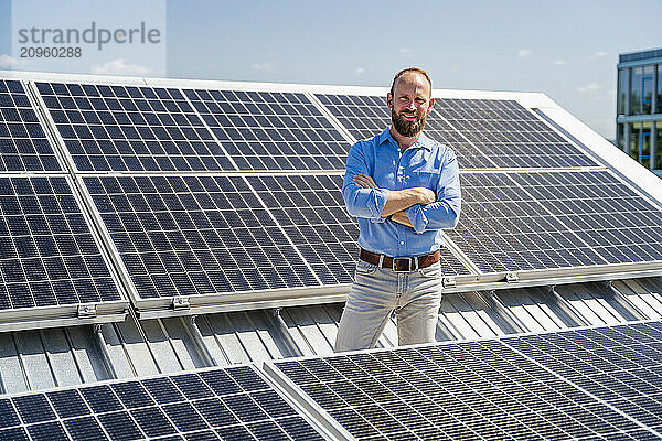 A self-assured businessman stands confidently amidst a field of solar panels